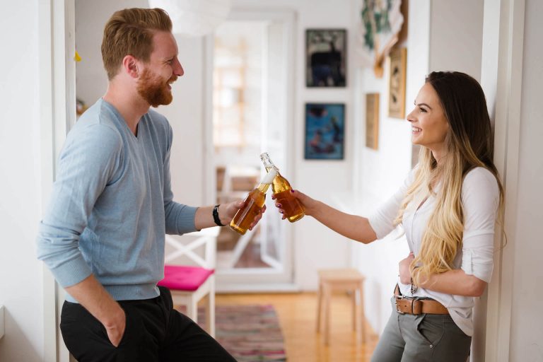 happy-couple-drinking-beer-and-toasting-at-home-UWT3974-1-1-768x512
